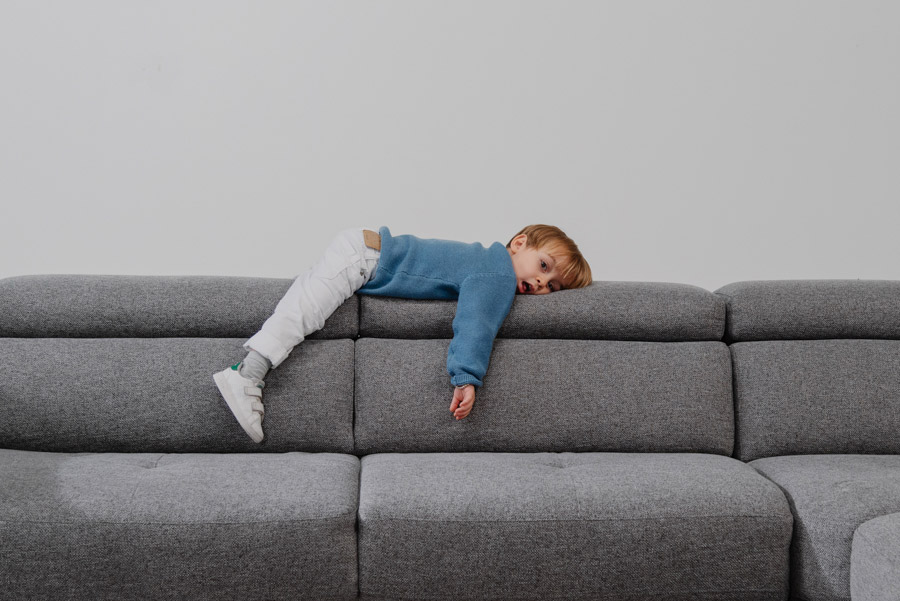 Bimbo steso su divano Natuzzi in tessuto di design made in Italy